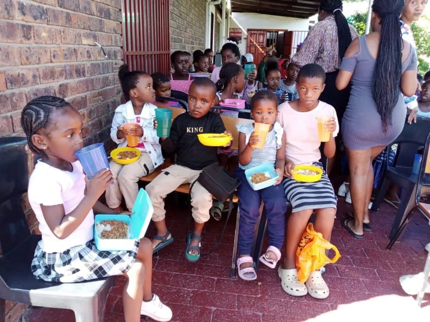 Children with lunchboxes and cold drinks after being served